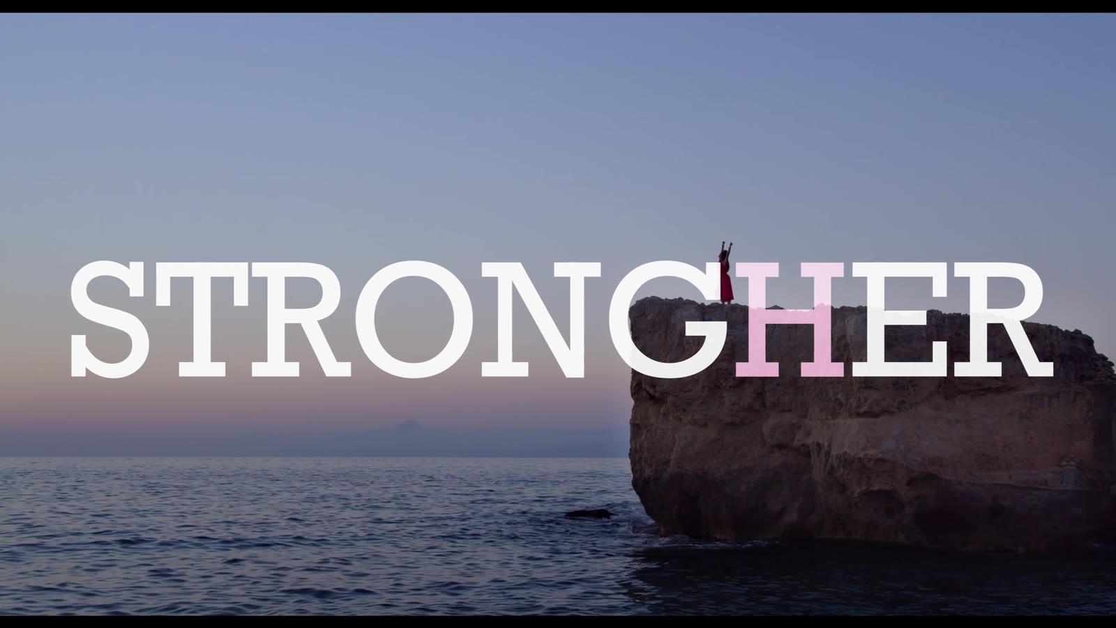 Il titolo StrongHer sul mare al tramonto, accanto a uno scoglio